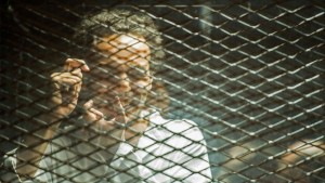 Photo of photojournalist Shawkan behind bars mimicking taking a photo