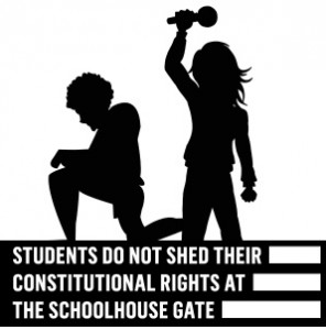 A student kneels another students holds a mic aloft. It reads “A student does not shed their constitutional rights at the schoolhouse gate” 