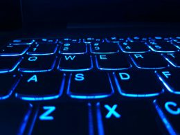 An illuminated computer keyboard. Glowing blue in the dark.